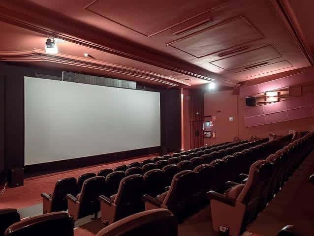 Sala de cine con butacas oscuras y techo decorado