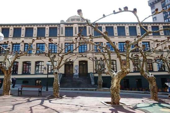 Fachada principal de La Campa de las Escuelas con árboles en primer plano
