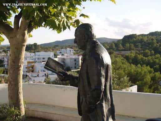 Estatua de Marià Villangómez leyendo un libro con vista a las casas blancas de Ibiza