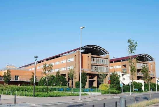 Vista exterior del Hospital Universitari d'Igualada con fachada de ladrillo y estructuras arqueadas bajo cielo despejado