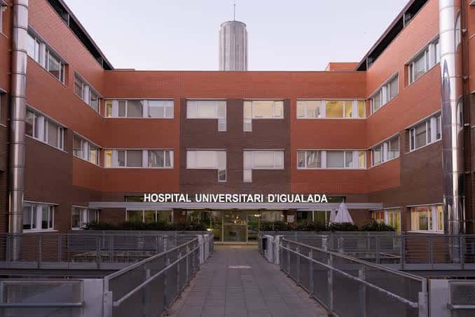 Entrada principal del hospital con letrero 'HOSPITAL UNIVERSITARI D'IGUALADA' y pasarelas peatonales