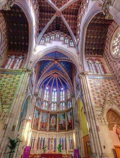 Interior del templo mostrando el techo abovedado y vitrales coloridos