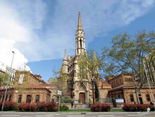 Fachada principal de la iglesia desde la calle con árboles en primer plano