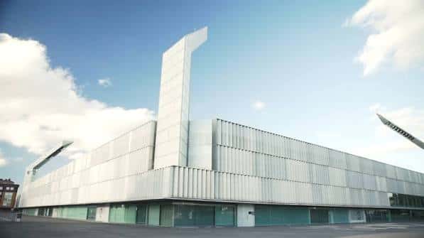 Fachada lateral del estadio mostrando detalles arquitectónicos en metal y cristal con diseño contemporáneo