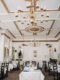 Sala de eventos o comedor elegante con lámparas de araña y mesas dispuestas