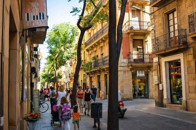 Calle estrecha y colorida típica de Gràcia con tiendas y transeúntes