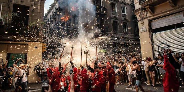 Celebración festiva con fuegos artificiales y multitudes en las calles de Gràcia