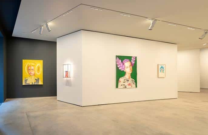 Espacio expositivo con paredes blancas y obras de arte coloridas