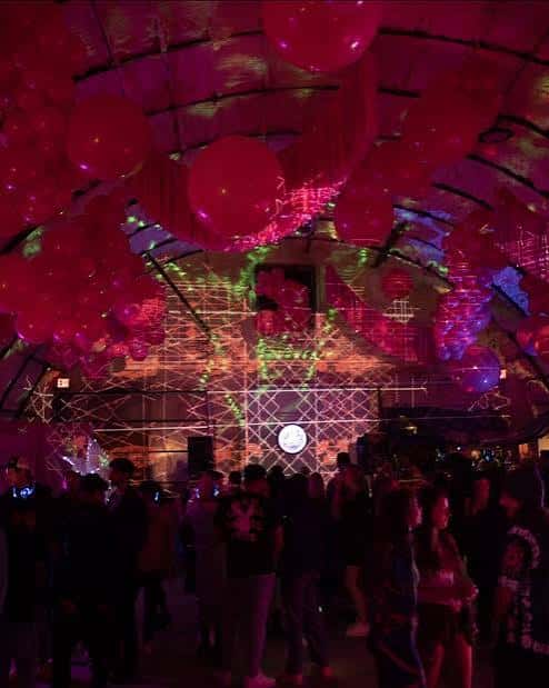 Fiesta nocturna en el interior con iluminación de neón y globos rojos colgando del techo