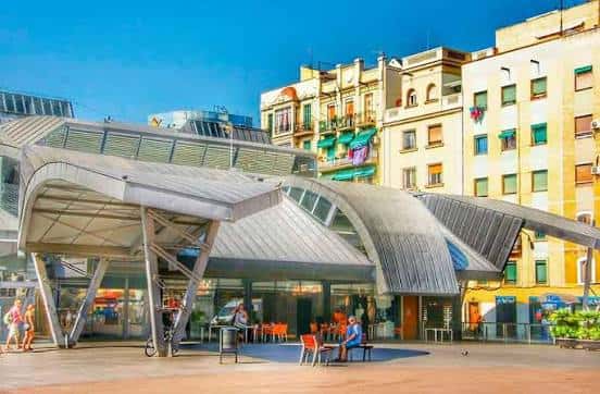 Fachada del mercado mostrando las estructuras metálicas curvas y el espacio público frente a él