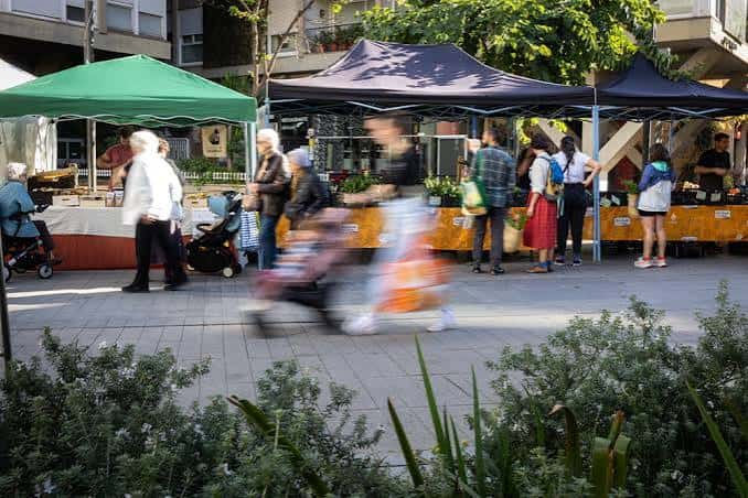 Vista general del Mercat de Pagès Germanetes con puestos bajo carpas y personas caminando