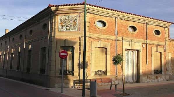Detalle arquitectónico de la esquina del edificio con azulejos decorativos y ventanas circulares en ladrillo visto