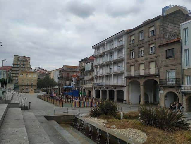 Vista general de la plaza con edificios históricos y zona de juegos infantiles