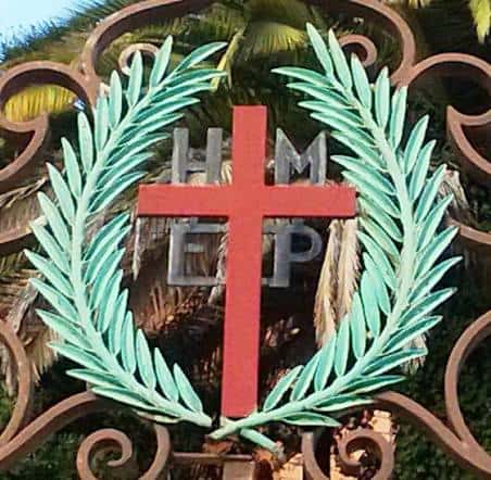 Detalle del emblema de la Fundación Santa Cruz con cruz roja y laurel verde