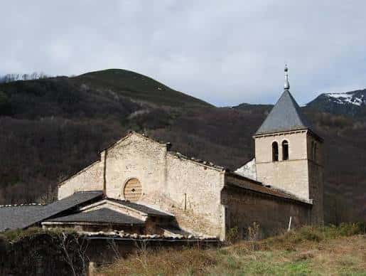 Fachada lateral del monasterio con su torre campanario bajo cielo nublado