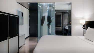 Habitación moderna con cama doble y baño de cristal