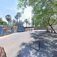 Vista de la calle Carrer de la Conreria con murales coloridos y palmeras