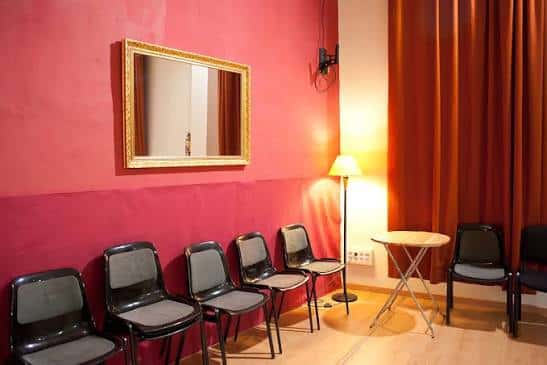 Sala de espera o sala de reuniones con sillas negras y espejo dorado