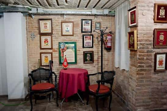 Salón con mesa redonda cubierta de rojo y pared de ladrillo decorada