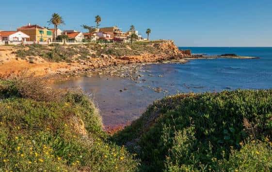 Vista panorámica de Cala de la Higuera con casas costeras y vegetación mediterránea