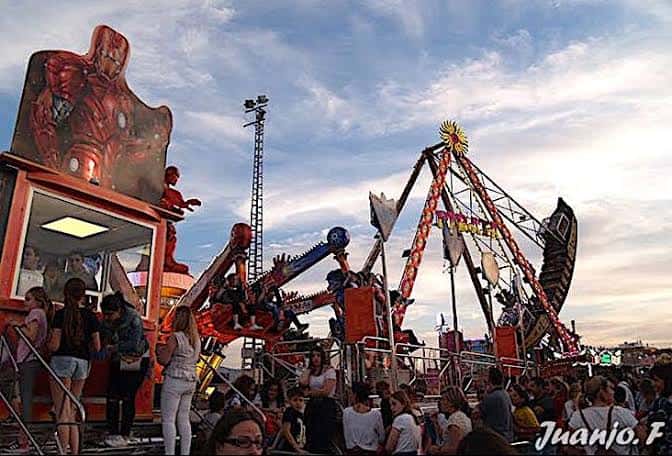 Atracciones de feria en movimiento con público disfrutando