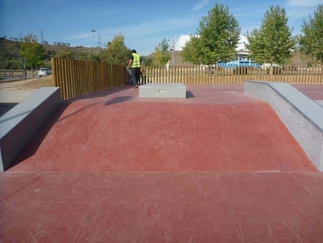 Vista general del skatepark con rampas rojas y valla de madera