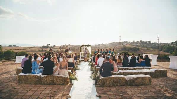 Ceremonia de boda al aire libre en el patio con invitados sentados sobre heno