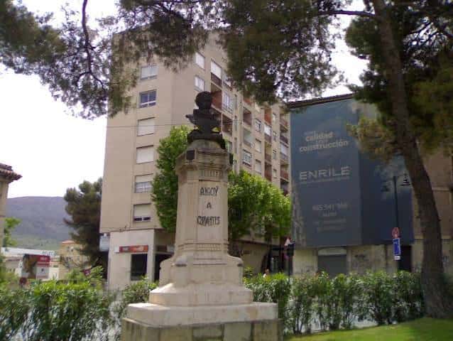 Monumento a Cervantes en el parque con edificios al fondo
