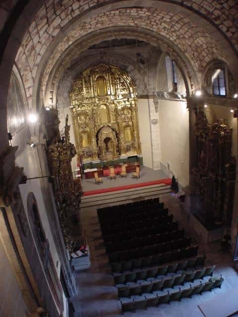 Perspectiva elevada del salón de actos mostrando la disposición de asientos y el retablo principal