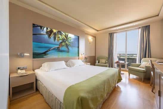 Habitación doble con cama king-size, decoración tropical y vistas al mar