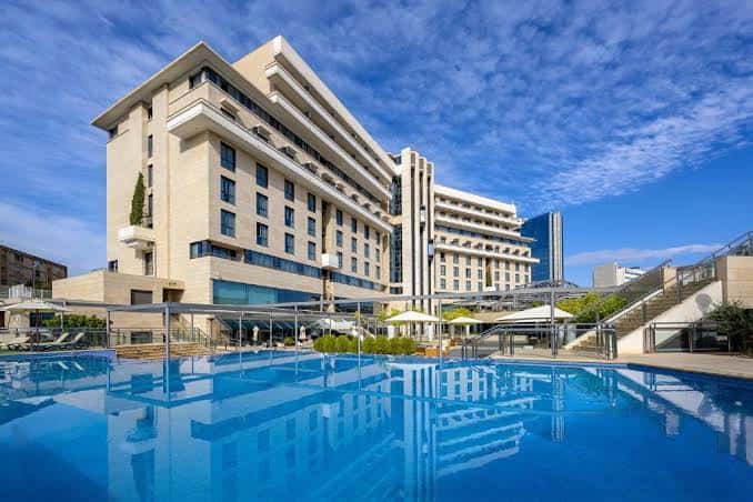 Vista exterior del Hotel Nelva con piscina al aire libre bajo cielo azul