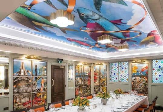 Sala de cenas privada con techo pintado y mesa larga decorada