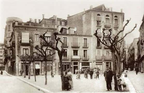 Fotografía histórica de la Plaça d'Anselm Clavé con personas y arquitectura antigua