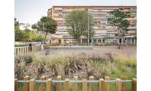 Área de juegos infantiles rodeada de vegetación y valla de madera