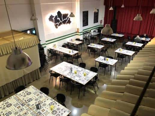 Vista general del salón de eventos con mesas dispuestas para una cena y gradas