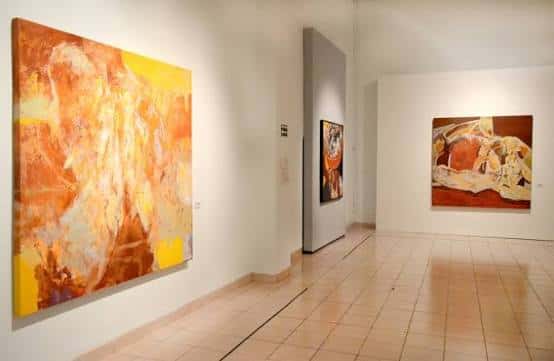 Salón de exposiciones con pinturas de tonos cálidos y diseño minimalista