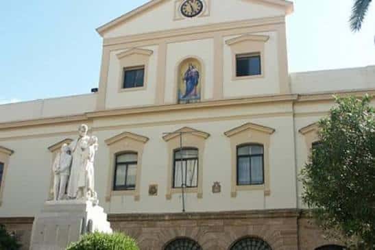 Detalle de la fachada con reloj y escultura religiosa