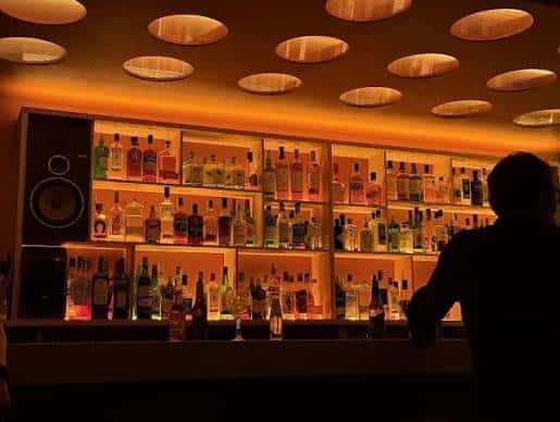 Interior del bar de Lumière Club con estanterías iluminadas y ambiente cálido