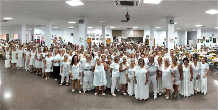 Gran reunión de personas vestidas de blanco en el salón principal del Centro Polivalente