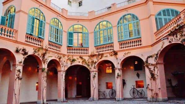 Patio interior con arcos, balcones y ventanas color rosa y turquesa