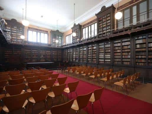 Sala de eventos en biblioteca con estanterías de madera y butacas dispuestas