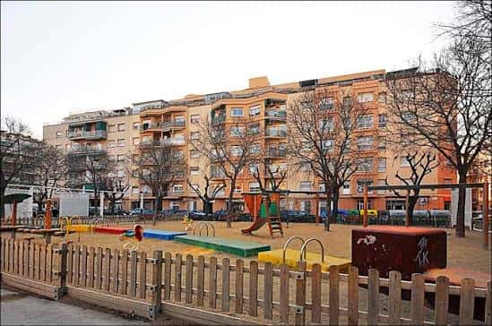 Vista general de la Plaça de Ramon Roigé i Badia con parque infantil y edificios residenciales al fondo