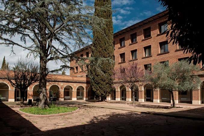 Patio interior con arcos de ladrillo, árboles centenarios y ambiente tranquilo para eventos