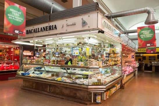 Interior del mercado mostrando una parada de bacalao con productos frescos y señalética local