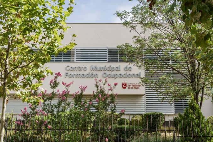 Fachada principal del Centro Municipal de Formación Ocupacional Marcelino Camacho con vegetación y cielo despejado