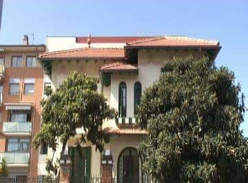 Fachada principal del Xalet Negre rodeado de árboles en un día soleado