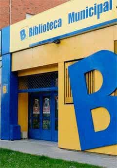 Entrada principal de la biblioteca con fachada amarilla y detalles en azul