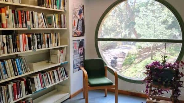 Rincón de lectura junto a ventana circular con vista al jardín