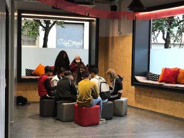 Sala de estar comunitaria con jóvenes conversando en zona de descanso