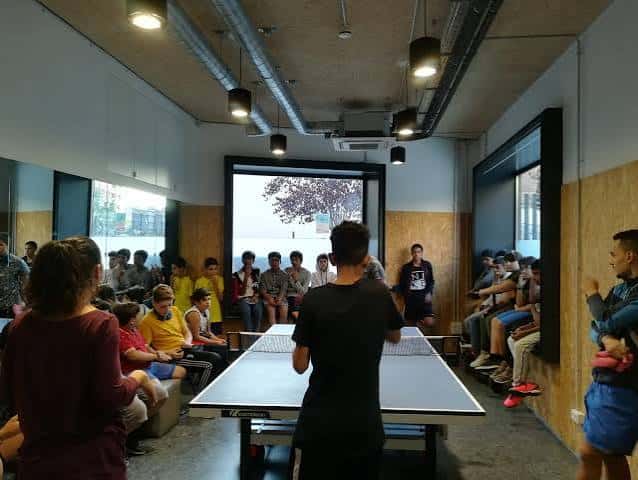 Actividad recreativa con mesa de ping-pong y público observando